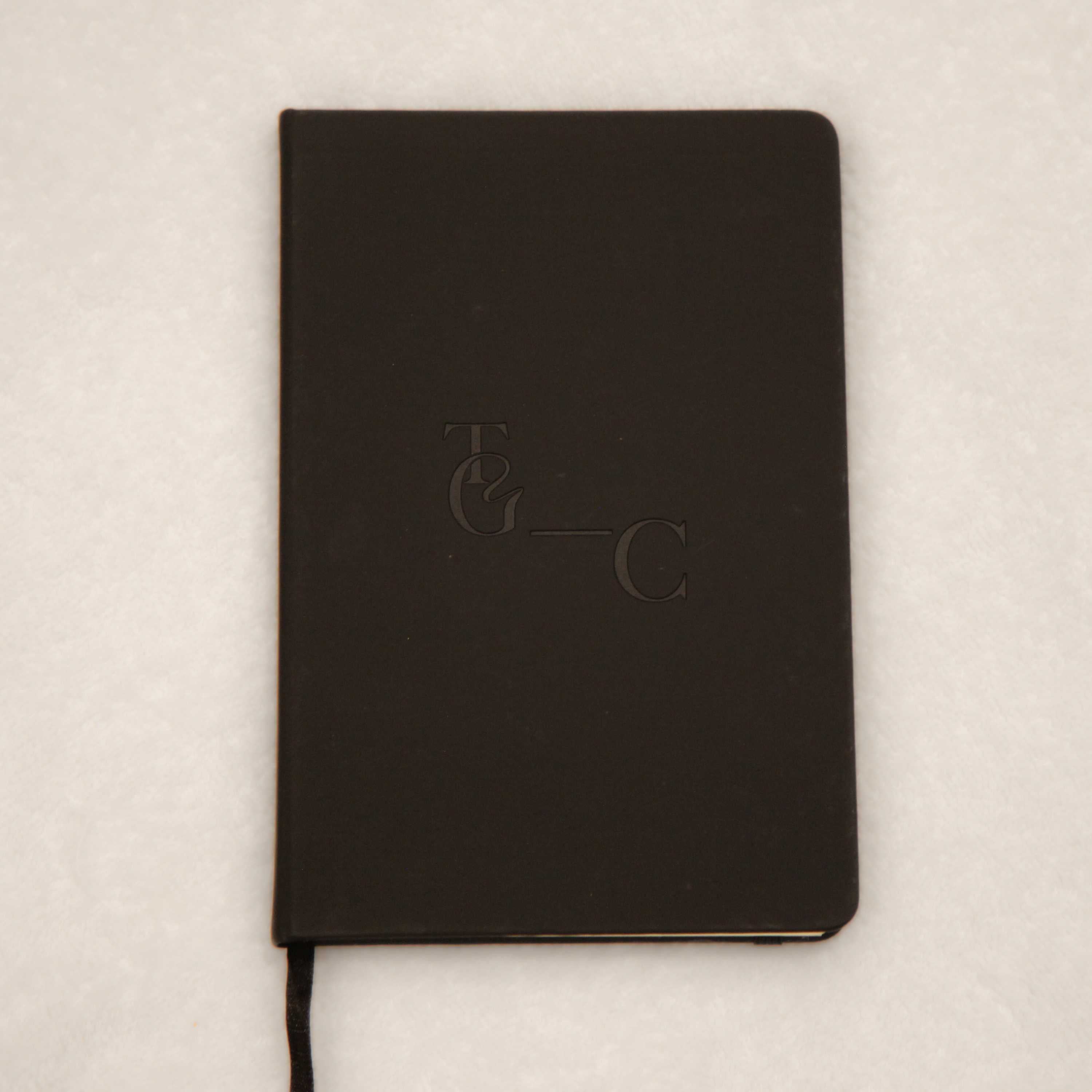 TGC black notebook on a light beige background