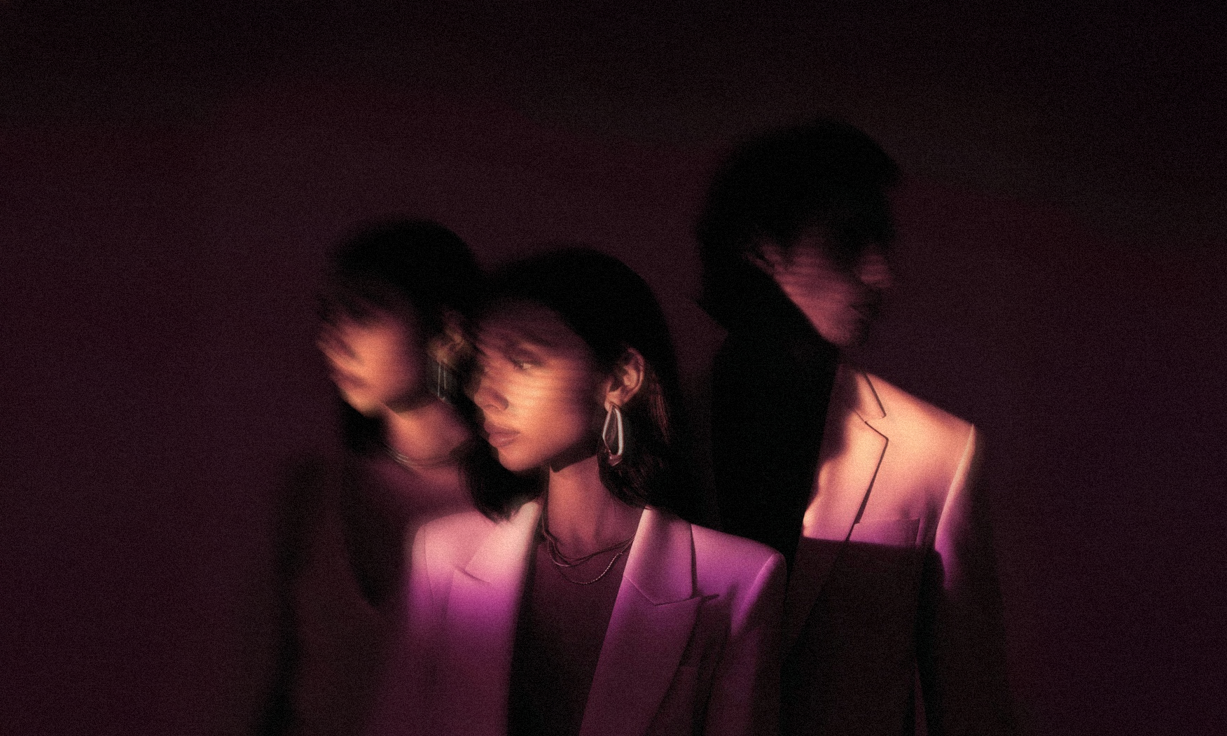 Three people standing close together with a dark, moody background. TGC Background Item. 